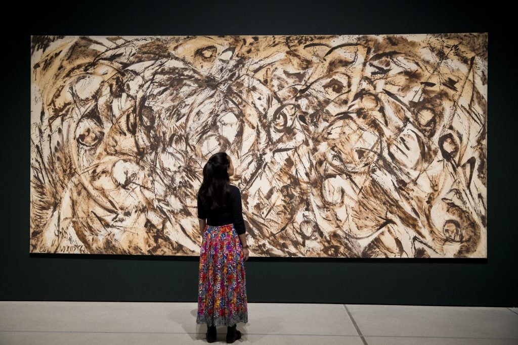 A woman looking at a large abstract painting with vivid brushstrokes